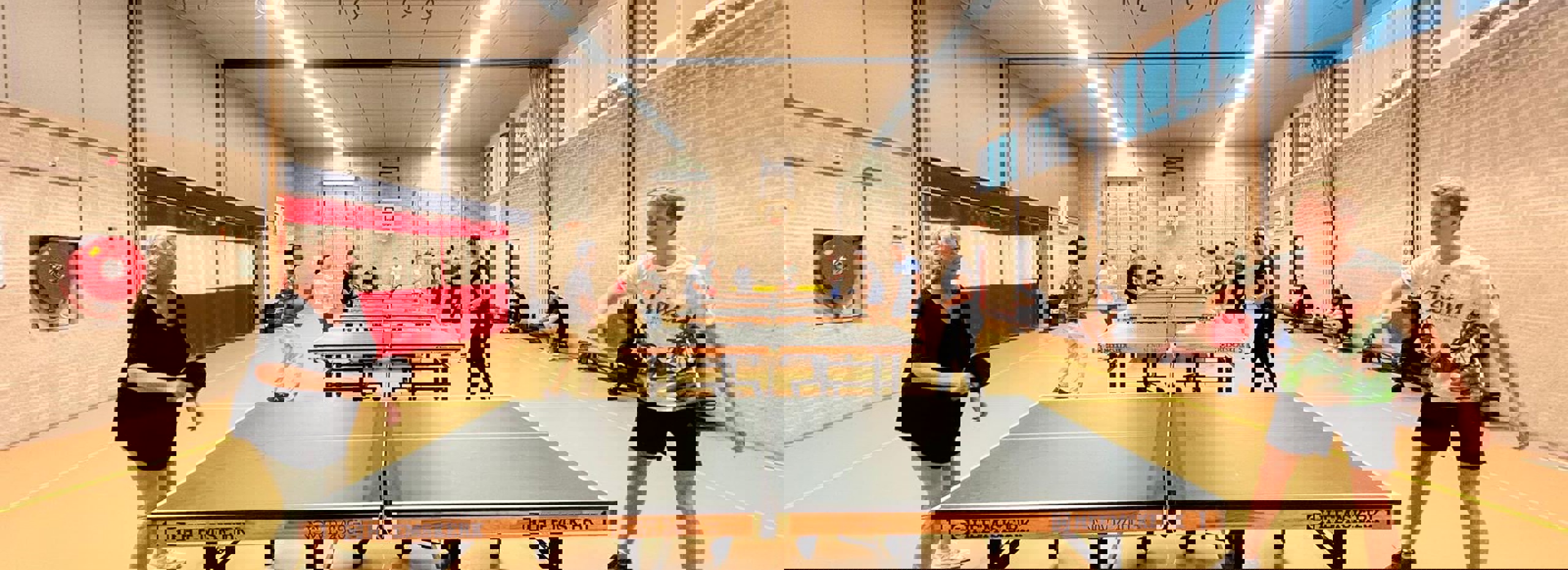 hall with table tennis tables and people playing table tennis