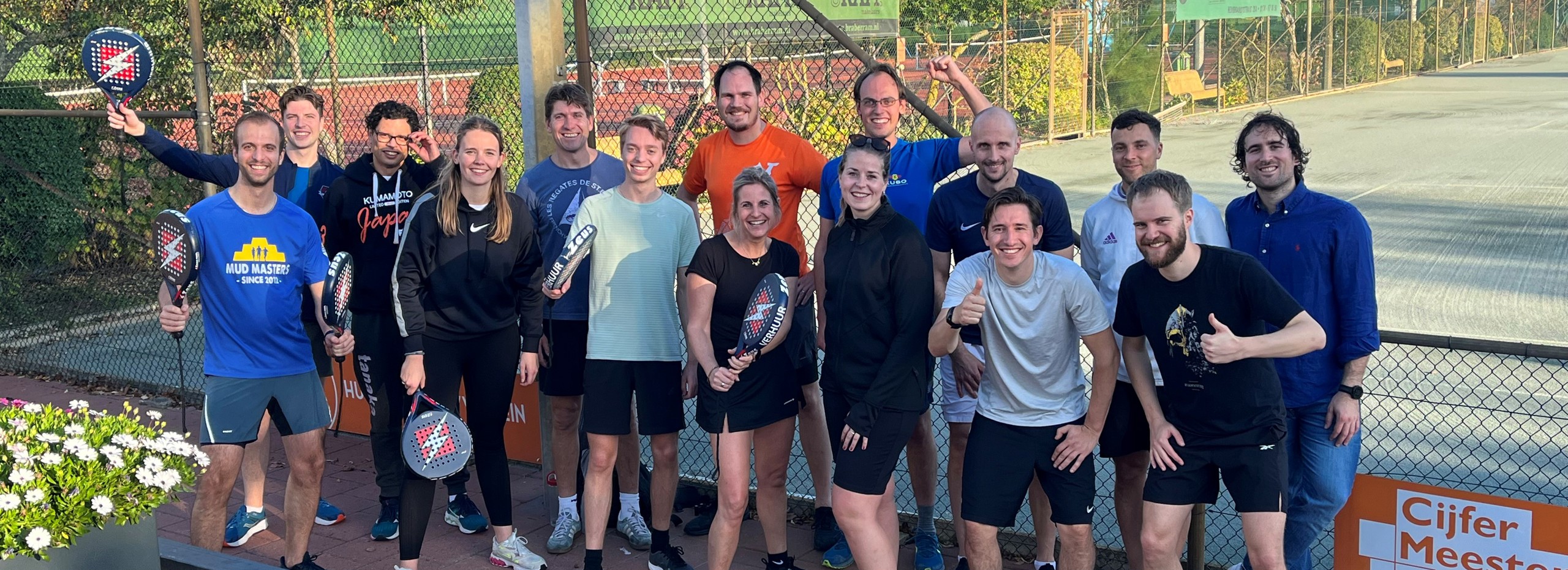 group of sporty people in front of a padel court and padel rackets in their hands